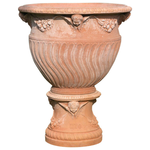 The most elegant and unusual in form, of the vases in the classic Poggi Ugo terracotta collection. Executed by hand with Impruneta clay with its famous frosty characteristics, the tortiglione vase is richly decorated with angel heads that intersperse the festoons of fruit and leaves with their wings.