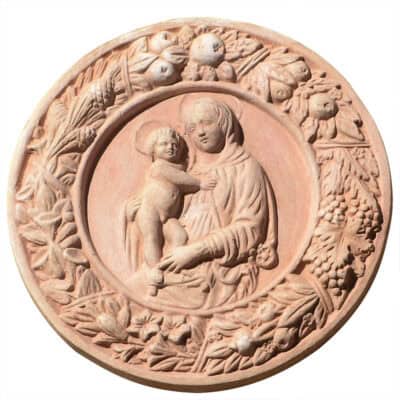 Tondo Vergine e Figlio in Ghirlanda in terracotta, dalla bottega dei Della Robbia, unisce arte, simbolismo e tradizione. Cerchio di frutta, verdura e gigli.