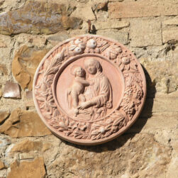 Round panel Garland with Virgin and Son in terracotta, inspired by the Della Robbia workshop, combines art, symbolism, and tradition. Circle of fruit, vegetables, and lilies.