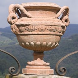 Stand to be placed on top of columns, capitals of fences, and on the sides of gates. Surface decorated with snake handles and festooned.