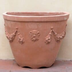 Sottocannella alta festonata in terracotta, tasca a parete per rampicanti e roseti. Forma elegante con decori classici. Realizzata a mano, ingeliva.