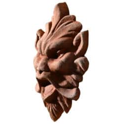 Terracotta mask relief depicting a demonic expressive face, symbolic architectural decoration