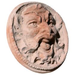 Mascherone circolare in terracotta con volto espressivo scolpito in rilievo decorativo