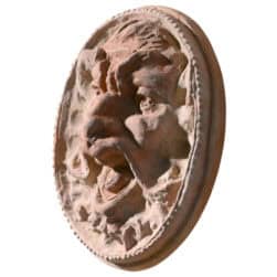 Mascherone circolare in terracotta con volto espressivo scolpito in rilievo decorativo