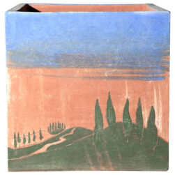 Cube flowerbox with cypressus and blue sky. Square Flower box. Inspired by Tuscany Hills. Shape of squared section with good capability of topsoil, moderate depth encumbrance, excellent wind stability, suitable for plants with moderate growth. Handmade, using Impruneta clay, resistant to frost up to – 30° C. Great duration, the form remains unchanged over the course of the time. The roots’ and plants’ health is improved by the good breathability of the terracotta, its thermal isolation, and the slow release of the humidity from the watering. The article acquires a beautiful exterior aspect over the course of the seasons.