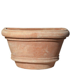 The Shallow wall pot with borders in terracotta, shaped like a half planter with decorative edges. Ideal for climbing plants. Perfect for terraces, gardens, and sidewalks.