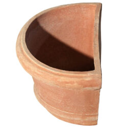 The Shallow wall pot with borders in terracotta, shaped like a half planter with decorative edges. Ideal for climbing plants. Perfect for terraces, gardens, and sidewalks.