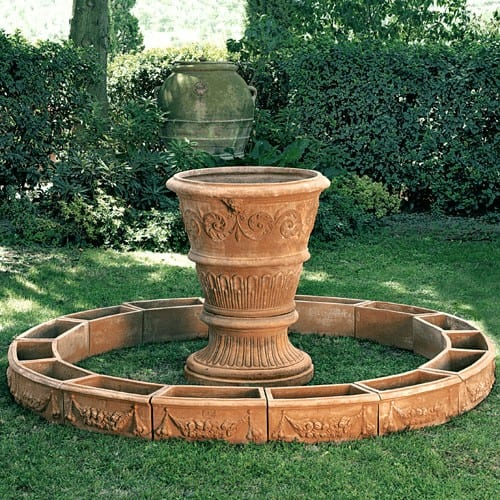 Vaso Decorato con Volute in terracotta toscana, con tralcio a rilievo e satiri scolpiti. Base ampia e stabile, ideale per alberelli e arbusti.