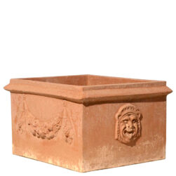 Cassetta due maschere in terracotta, con maschere grottesche e festoni, è ideale per piante e fioriture, unendo tradizione e simbolismo storico.